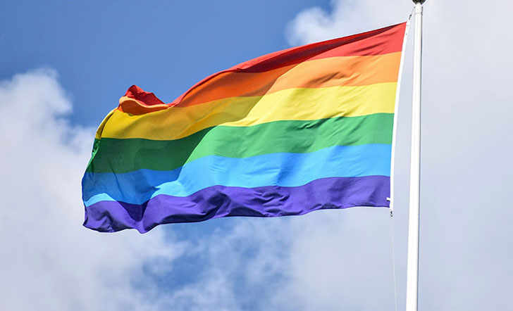 Regenbogenfahne vor teils bewölktem Himmel. Regenbogenfahne vor teils bewölktem Himmel.