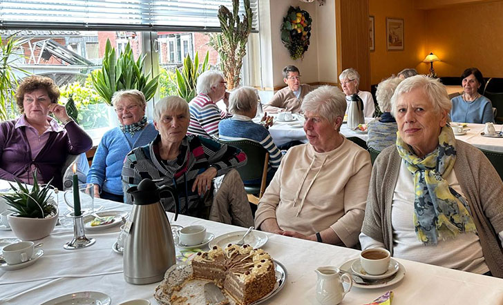 Eine Gruppe Frauen an einer Kaffeetafel. 