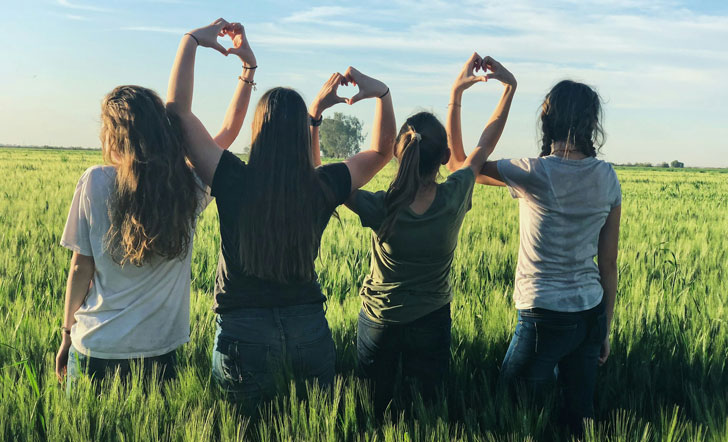 Vier junge Frauen bilden aus ihren Händen Herzsymbole.