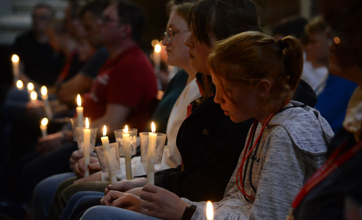 Jugendliche mit Kerzen in einer Kirchenbank