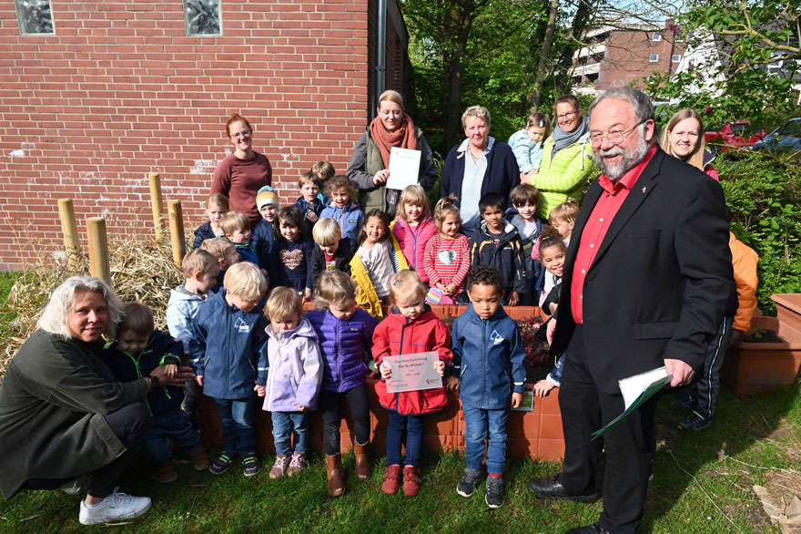 Kinder und Erzieherinnen der Kita St. Michael 1 freuen sich mit Kathy Hürländer (hinten 2. von links), Doris Hoeter (hinten Mitte) und Thomas Kamp-Deister (rechts) über die erfolgreiche Auszeichnung als „ökofaire Einrichtung“. 